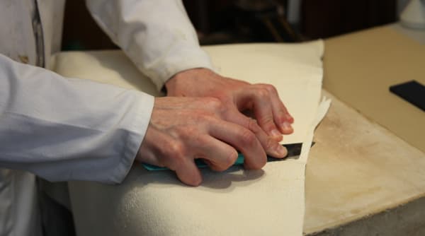 A razor-sharp knife is used to start the paring of the covering skin, which is thinned down in the areas where it is turned in around the boards and at the head and tail of the spine.