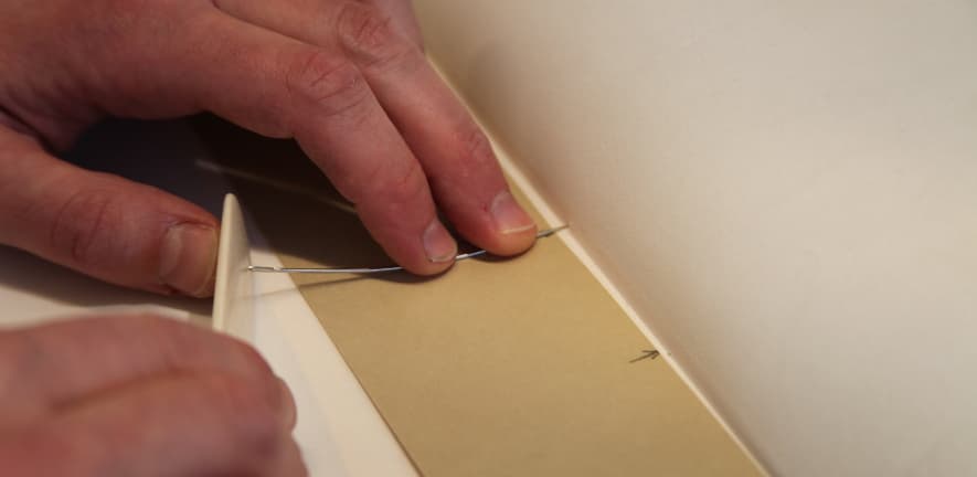 The main sewing holes are pierced through the parchment, alum-tawed skin and waste sheet in such a way as to avoid the holes showing in the finished joint.